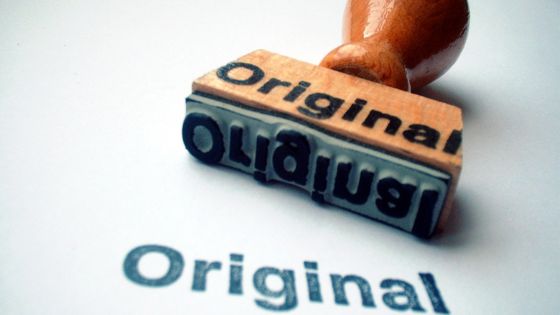 Stamp with the word original on the rubber part and the word Original stamped on paper represnting the importance of authentic content on social media.